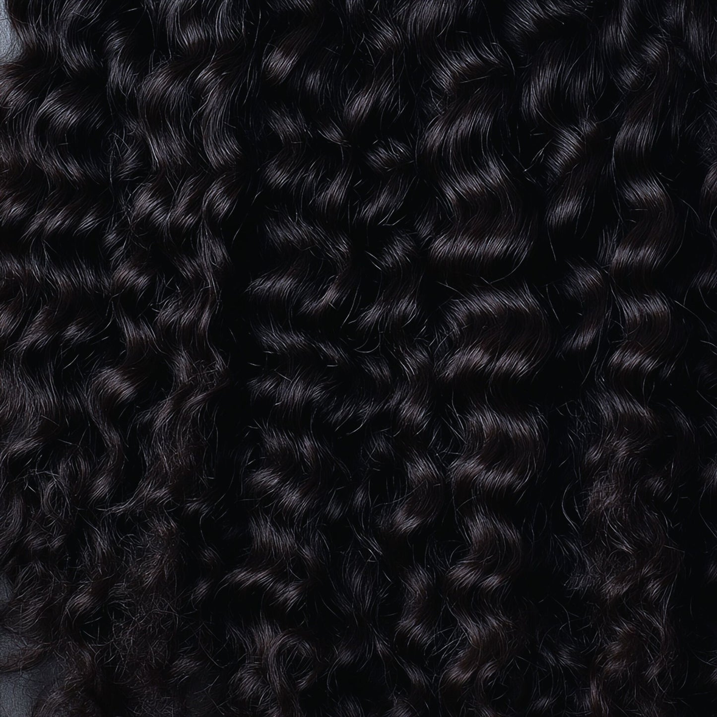 Close-up of Raw Burmese Curly hair, showcasing its defined curls, natural luster, and soft texture for a voluminous look.